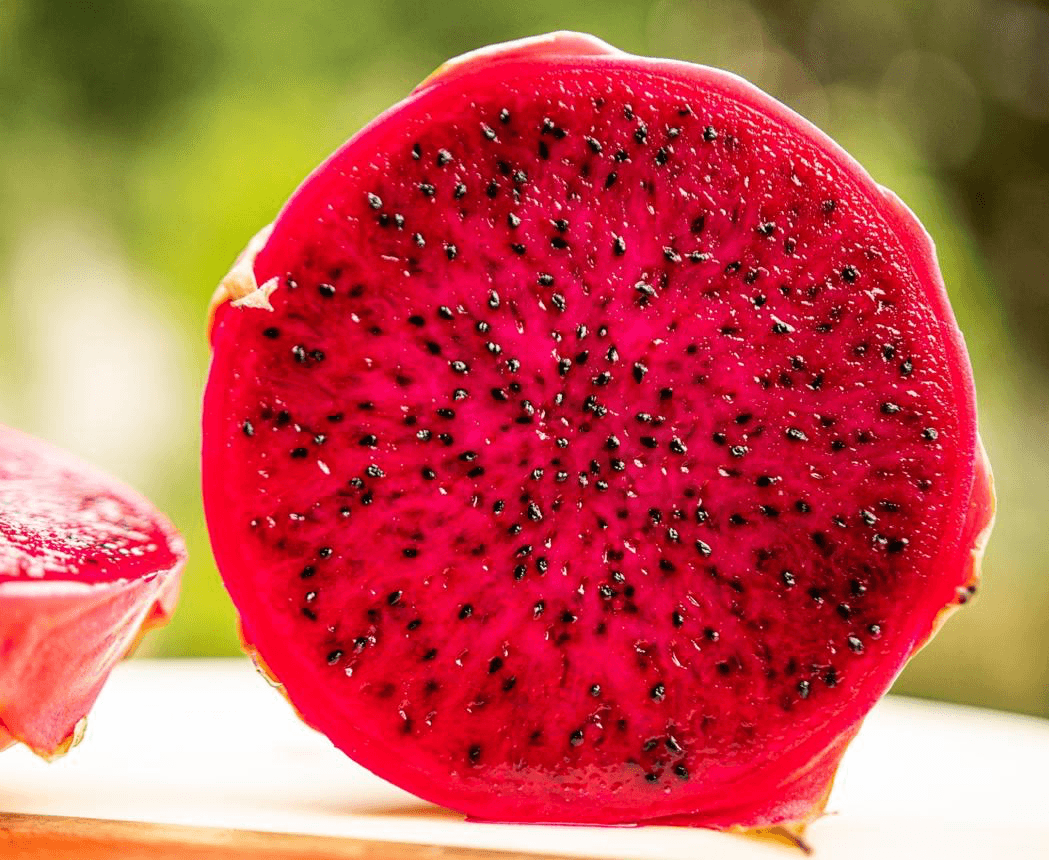 Fresh red dragon fruit cross-section showing vibrant magenta flesh with black seeds